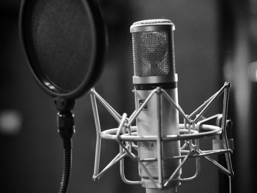 grayscale photo of condenser microphone beside pop filter