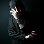 a man in a black hoodie covering his face with his hands