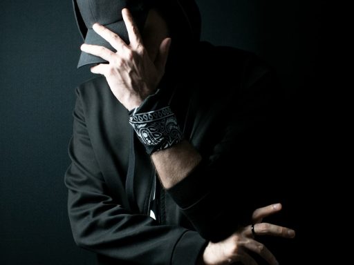 a man in a black hoodie covering his face with his hands