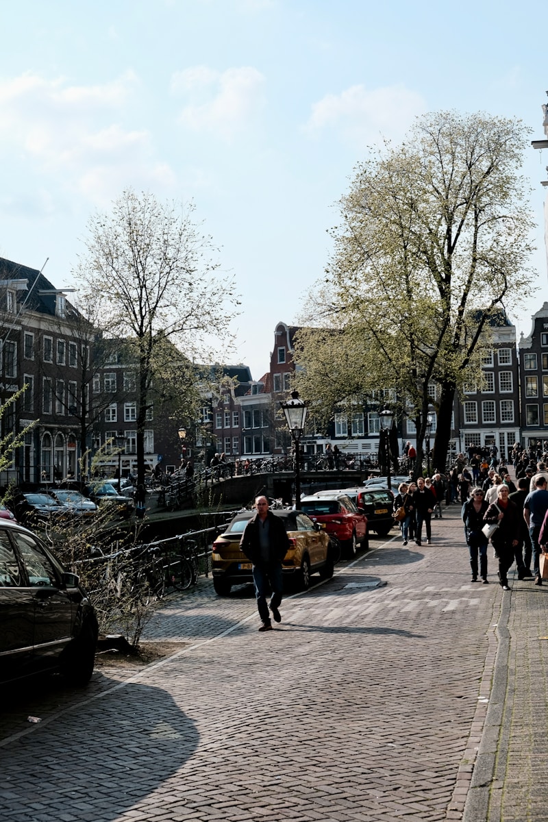 a group of people walking down a street next to parked cars