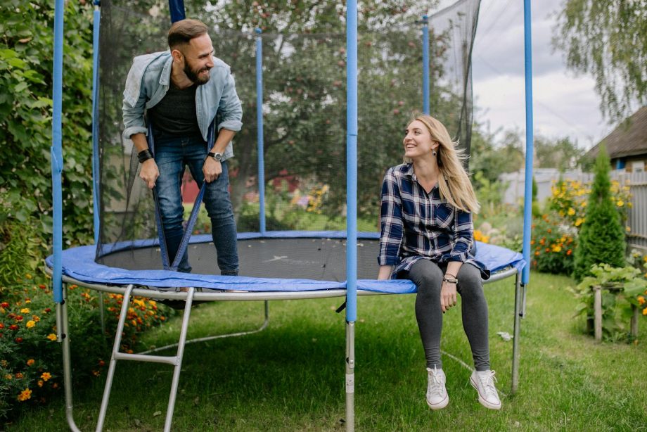 Smiling couple bonding on a trampoline surrounded by greenery and flowers.
