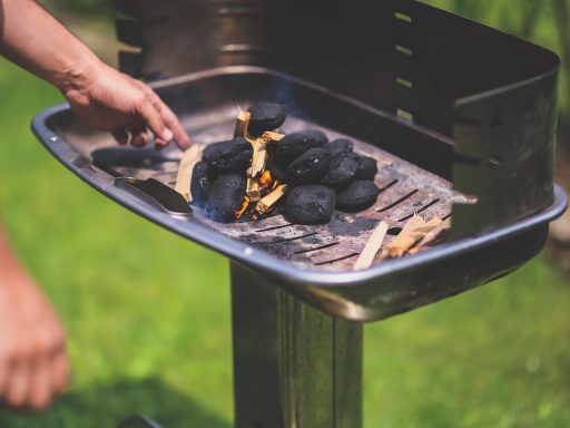Man staat bij een barbecue buiten te grillen op een zomerse dag