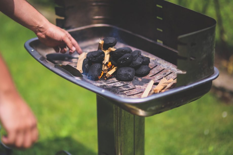 Man staat bij een barbecue buiten te grillen op een zomerse dag