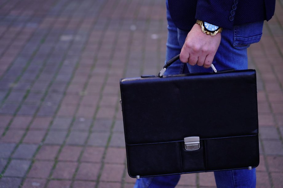 Man met een leren messenger bag over zijn schouder in stedelijke omgeving