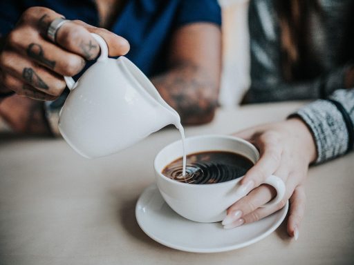 Man in antracietkleurige badjas aan de ontbijttafel met een kop koffie