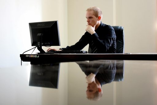 Man achter een opgeruimd bureau met laptopstandaard, toetsenbord en andere bureau gadgets