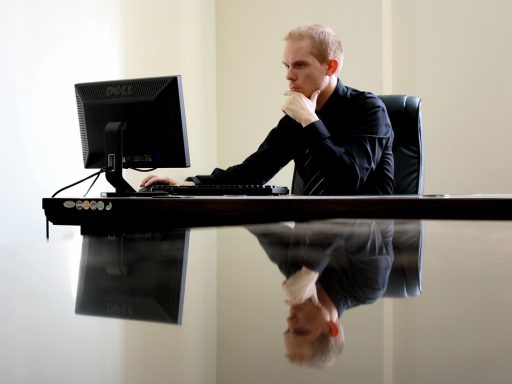 Man achter een opgeruimd bureau met laptopstandaard, toetsenbord en andere bureau gadgets